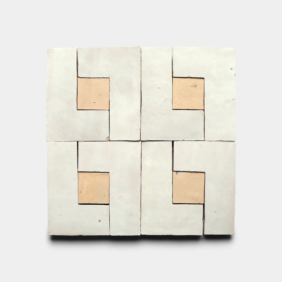 The Rubric 1 Sample by Zia Tile features four square cement tiles in a grid, each with a geometric tan center and pale L-shapes for a symmetrical, modern look on a light background.