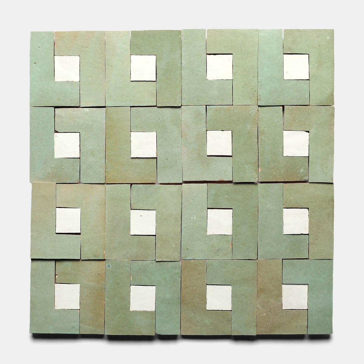 Sixteen square green Rubric 4 tiles by Zia Tile, each featuring a white square near the center and geometric cutouts that create a repeating interlocking pattern on a light gray background.