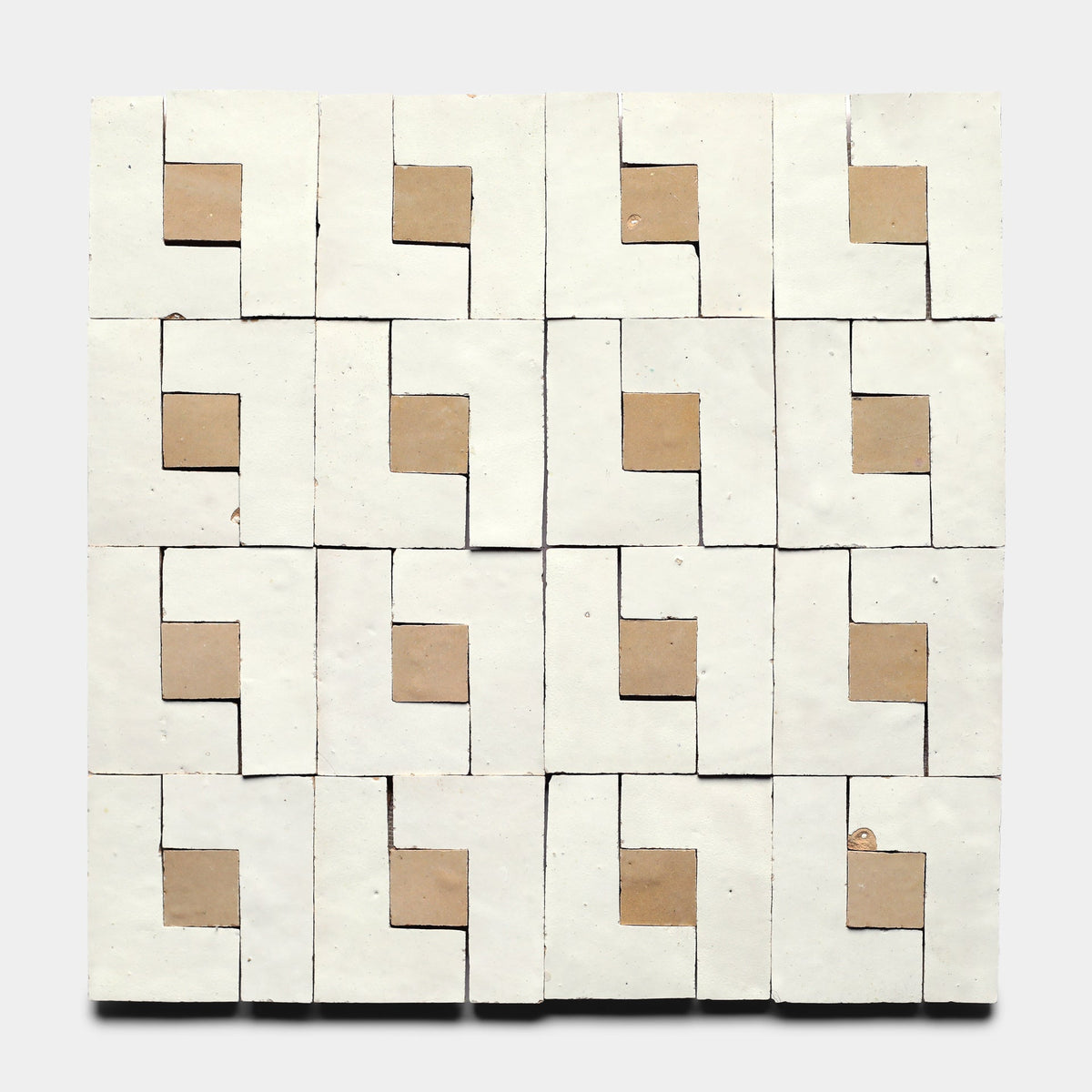 The Rubric 6, Sample by Zia Tile showcases a square artwork with a grid of handcrafted tiles, each cut-out corner revealing a brown square beneath and forming a geometric, repeating pattern on a light background.