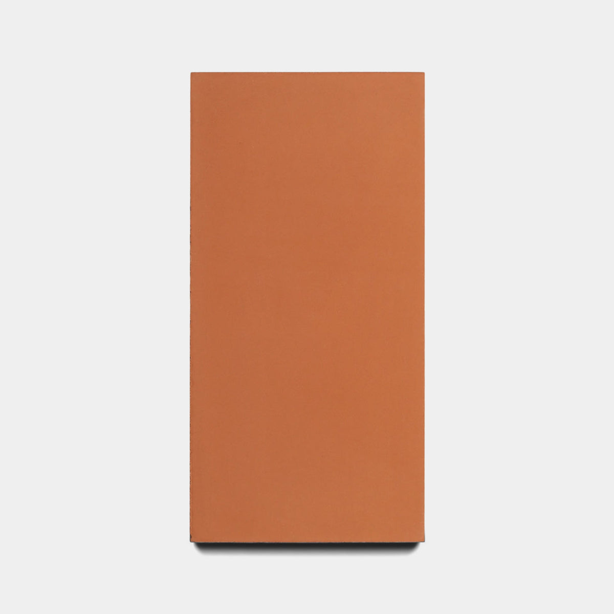 A Rust 4x8 Sample brick by Zia Tile stands vertically against a white background, highlighting its simple, rectangular terracotta form.