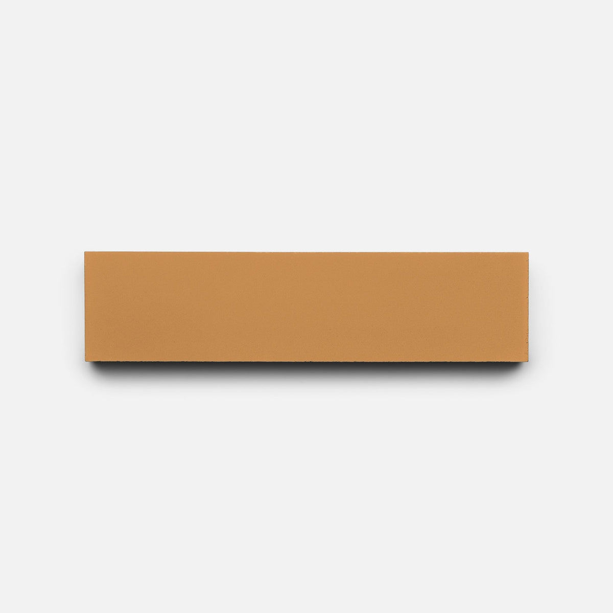 A rectangular, flat Saddle 2x8 brick sample by Zia Tile in tan is centered on a plain white background with a subtle shadow beneath it.