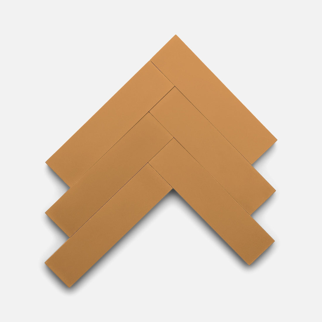 Four rectangular Saddle 2x8 tiles by Zia Tile, in a tan shade, are arranged in a herringbone pattern against a plain white background.