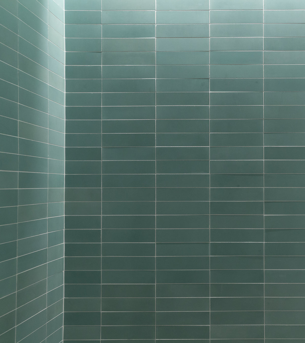 A clean, empty wall is tiled in a grid pattern with Sage 2x8 subway tiles from vendor-unknown in teal. The two walls meet at a corner, and evenly spaced light grout lines give a crisp, modern appearance.