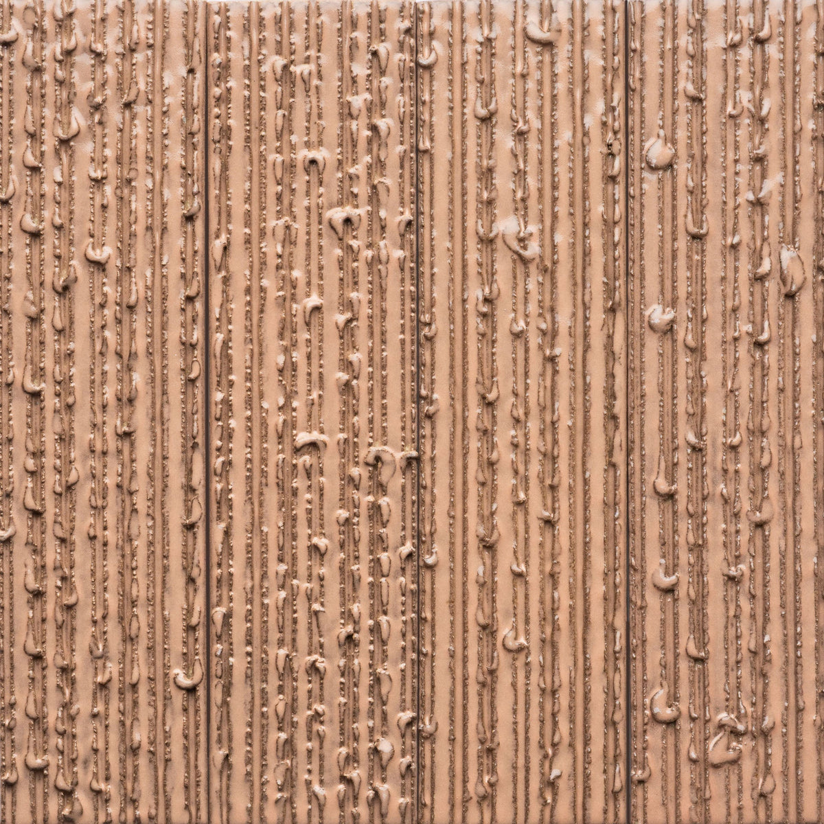 Close-up of Sakura + Furrowed, Sample by Zia Tile—showing a textured light brown surface with vertical lines and ridges, resembling melted chocolate or a creamy substance spread in straight patterns.