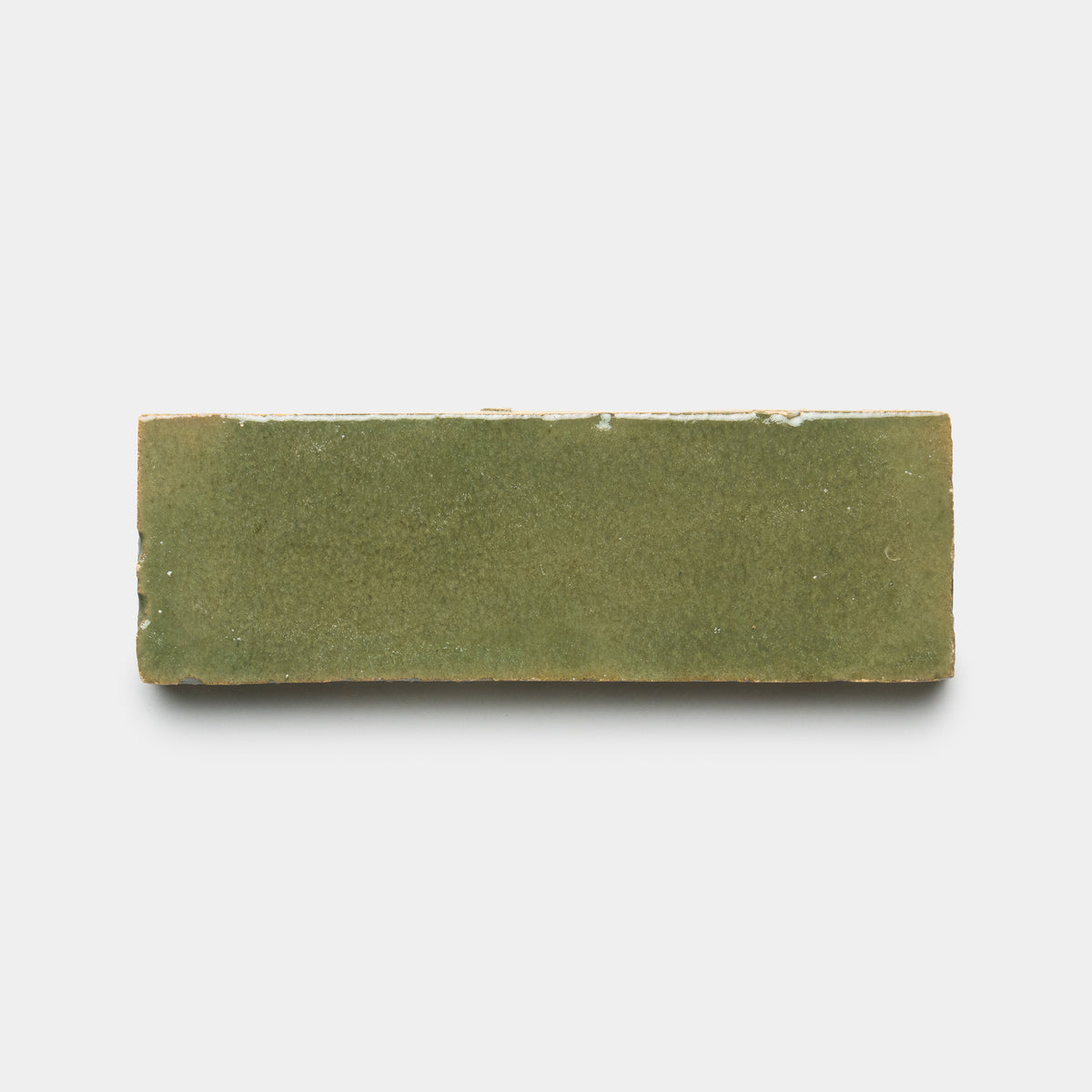 The Savanna 2x6 by Zia Tile is a rectangular ceramic tile featuring a smooth, matte olive-green surface, shown from above on a plain white background.