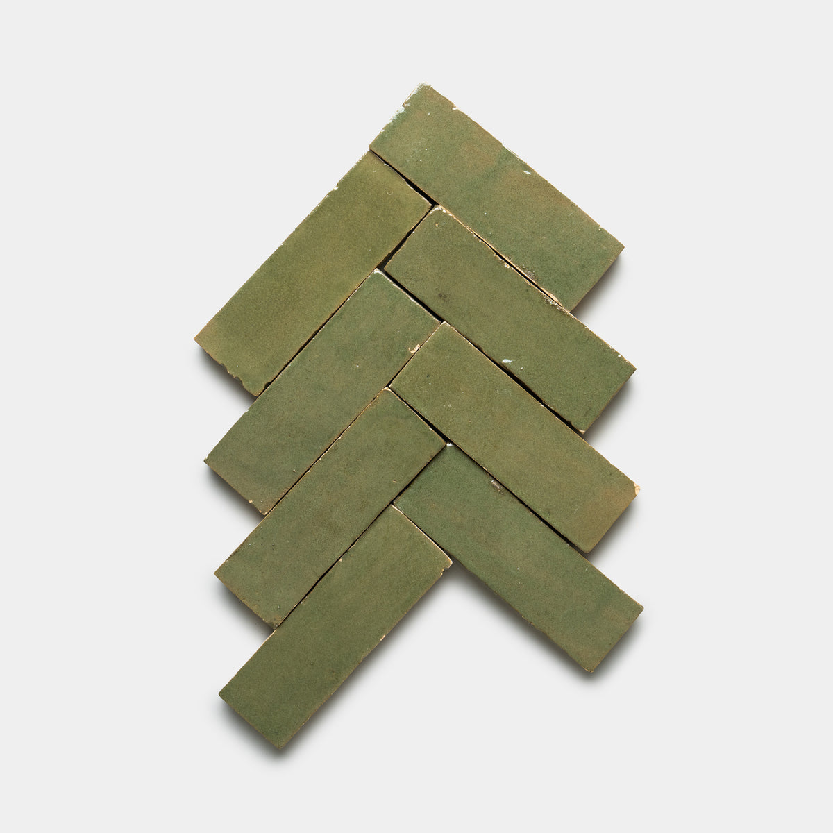 Six Savanna 2x6 tiles by Zia Tile, in rectangular green shapes, are arranged in a herringbone pattern on a white background to form an upward-pointing arrow shape.