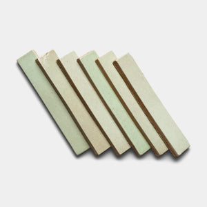 Six Sayulita Mini Bar tiles by Zia Tile, in light green ceramic and rectangular shape, are arranged diagonally in a neat, overlapping row on a white background.