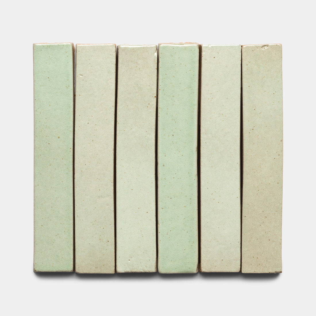 Six rectangular Sayulita Mini Bar ceramic tiles by Zia Tile are vertically aligned side by side on a white background. The pale green tiles have a smooth, slightly glossy finish with subtle color variations.
