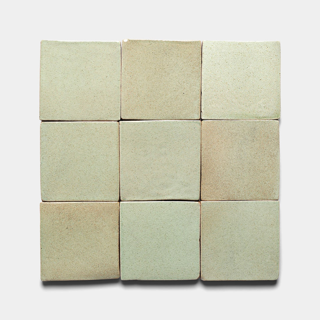 Nine Sayulita 4x4 Square tiles by Zia Tile, in light beige and pale green, are arranged in a 3x3 grid. These handmade ceramic tiles feature a slightly uneven matte surface with subtle color variations.