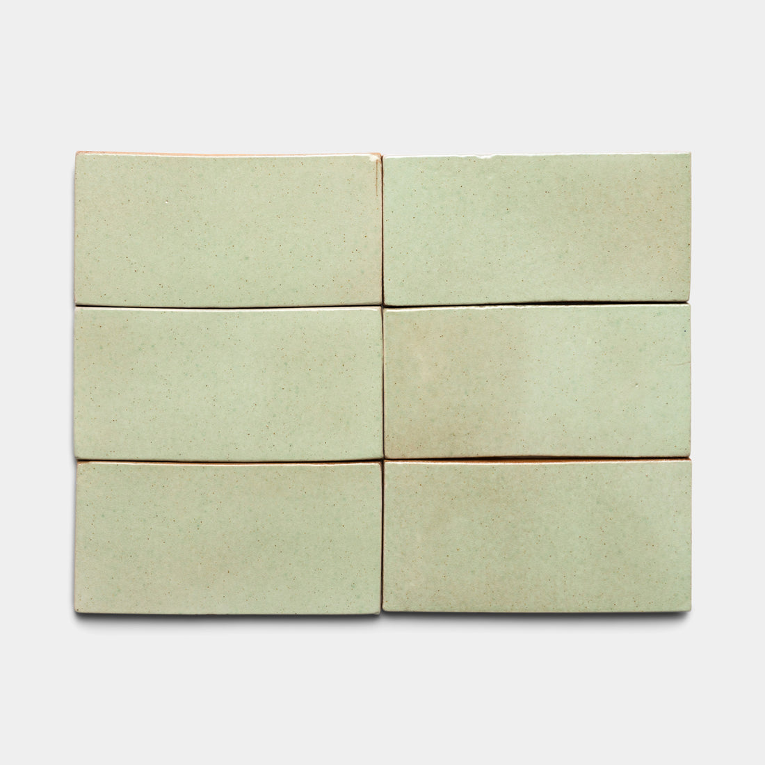 Six Sayulita 4x8 Rectangle tiles by Zia Tile, in pale green ceramic with a smooth matte finish and slightly uneven edges, are arranged in two rows of three on a light gray background.