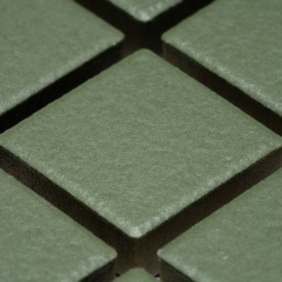 Close-up of Zia Tile's Sequoia 1x1 tiles, showcasing a textured green surface with square tiles arranged in a grid and visible gaps between them.