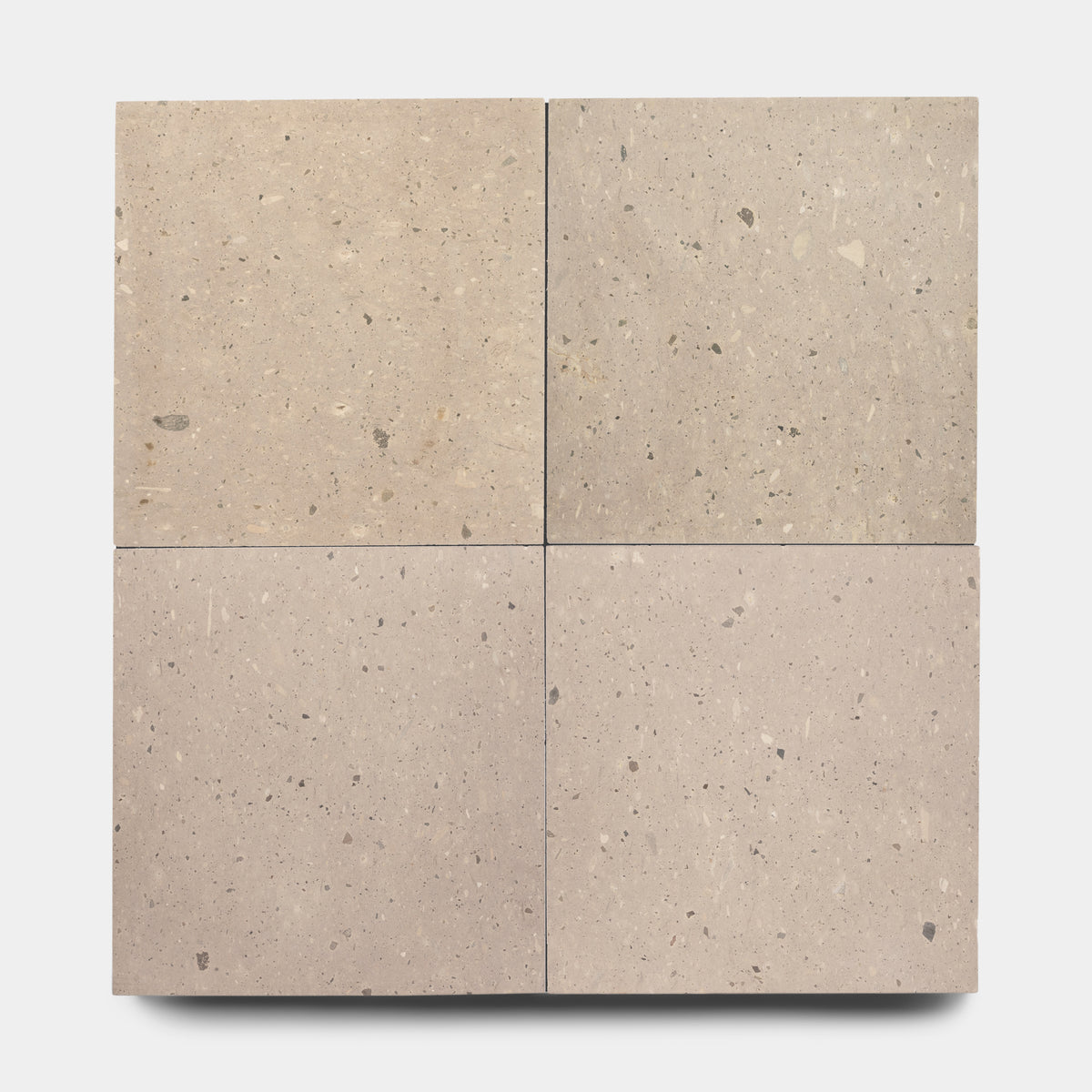 Four Sierra 24x24 tiles from Zia Tile are arranged in a 2x2 grid on a light background, highlighting the natural variations and earth-toned aggregates of Mexican volcanic Cantera stone.