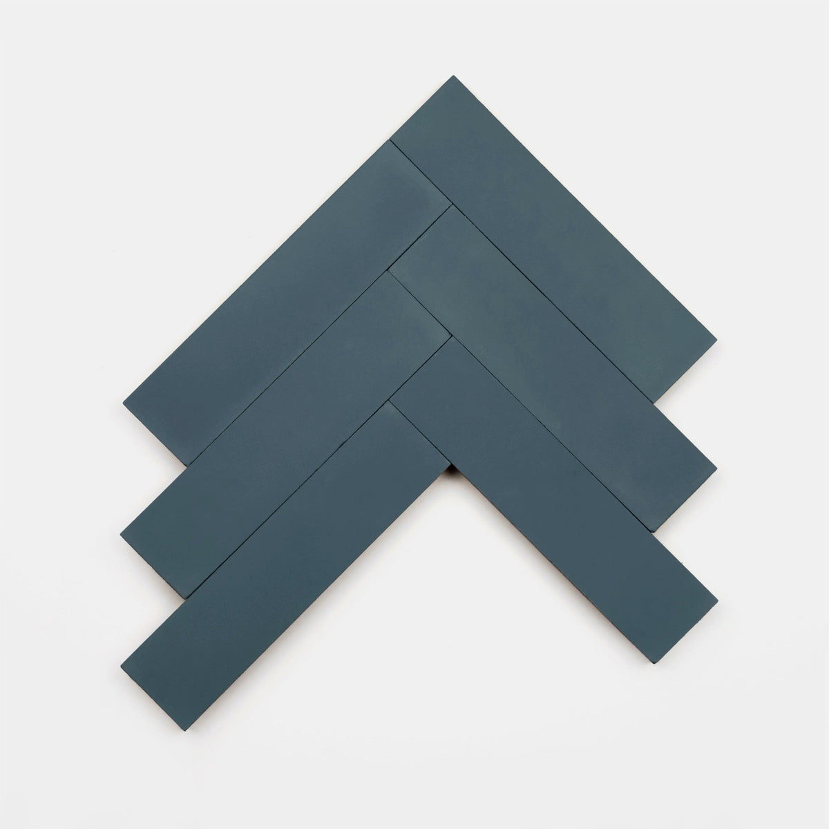 Five Saddle 2x8 tiles by Zia Tile, in dark blue, are arranged in a herringbone pattern on a white background to form an upward-pointing arrow shape.