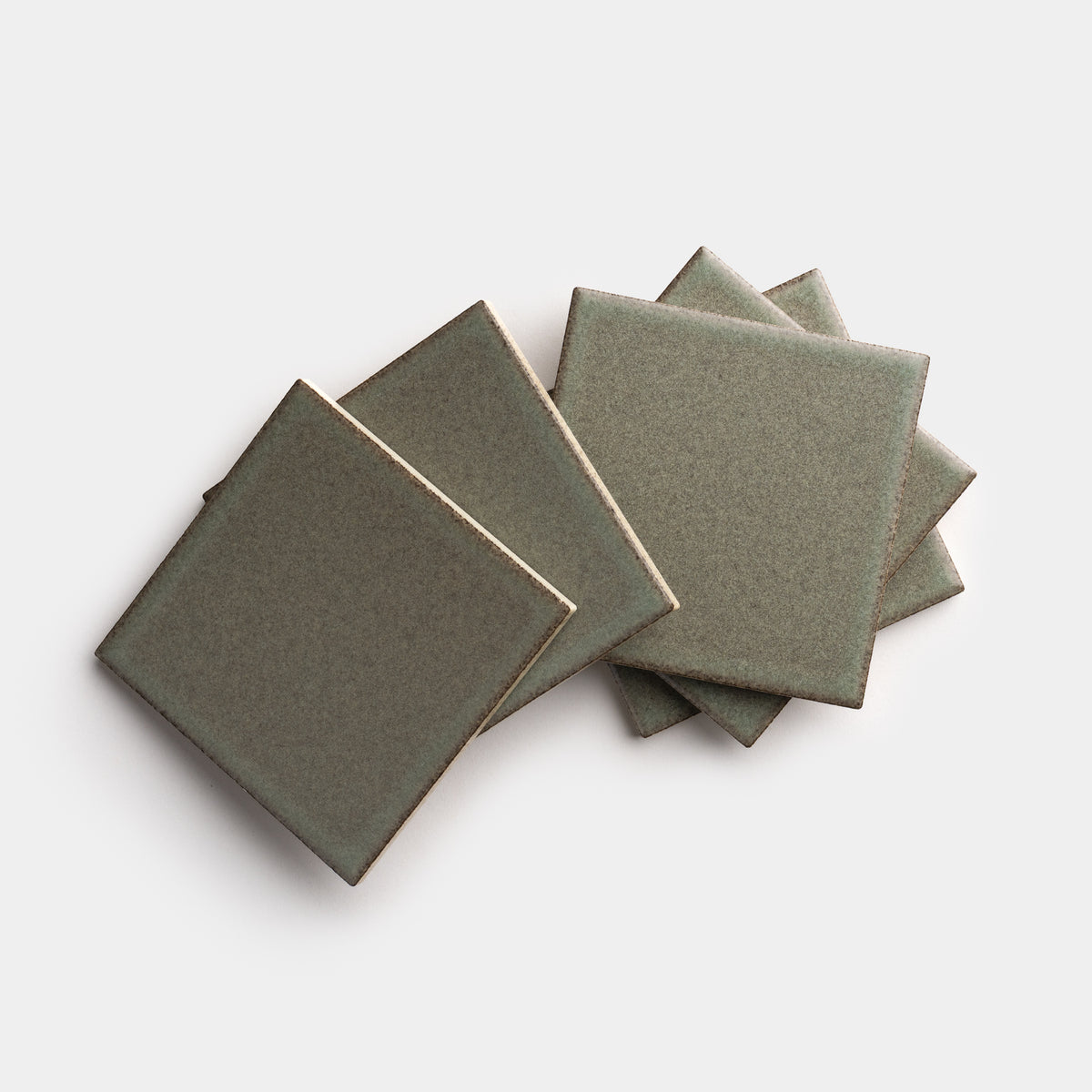 Four Spanish Moss 4x4 ceramic tiles from Zia Tile are arranged in a slightly overlapping, fanned-out pattern on a plain white background.