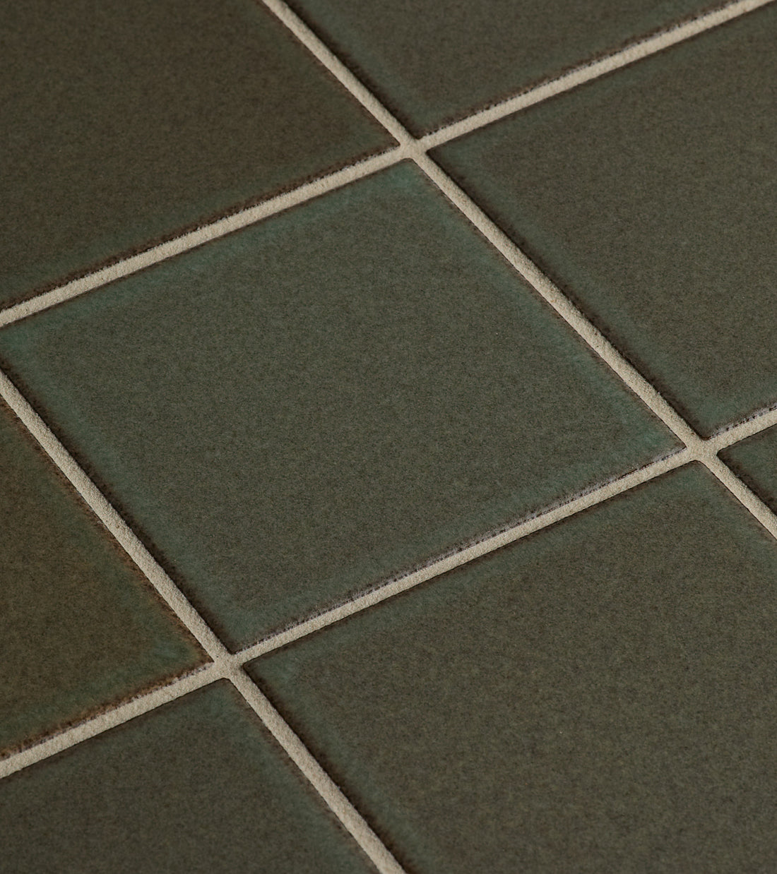 Close-up of Zia Tile's Spanish Moss 4x4 tiles, featuring a greenish-grey hue, beige grout lines, subtle color variations, and a smooth matte finish in a classic grid pattern.