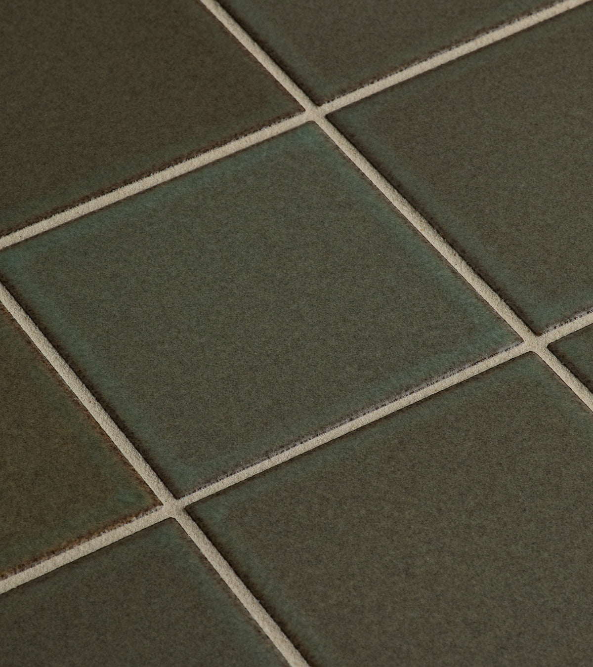 Close-up of Zia Tile's Spanish Moss 4x4 tiles, featuring a greenish-grey hue, beige grout lines, subtle color variations, and a smooth matte finish in a classic grid pattern.