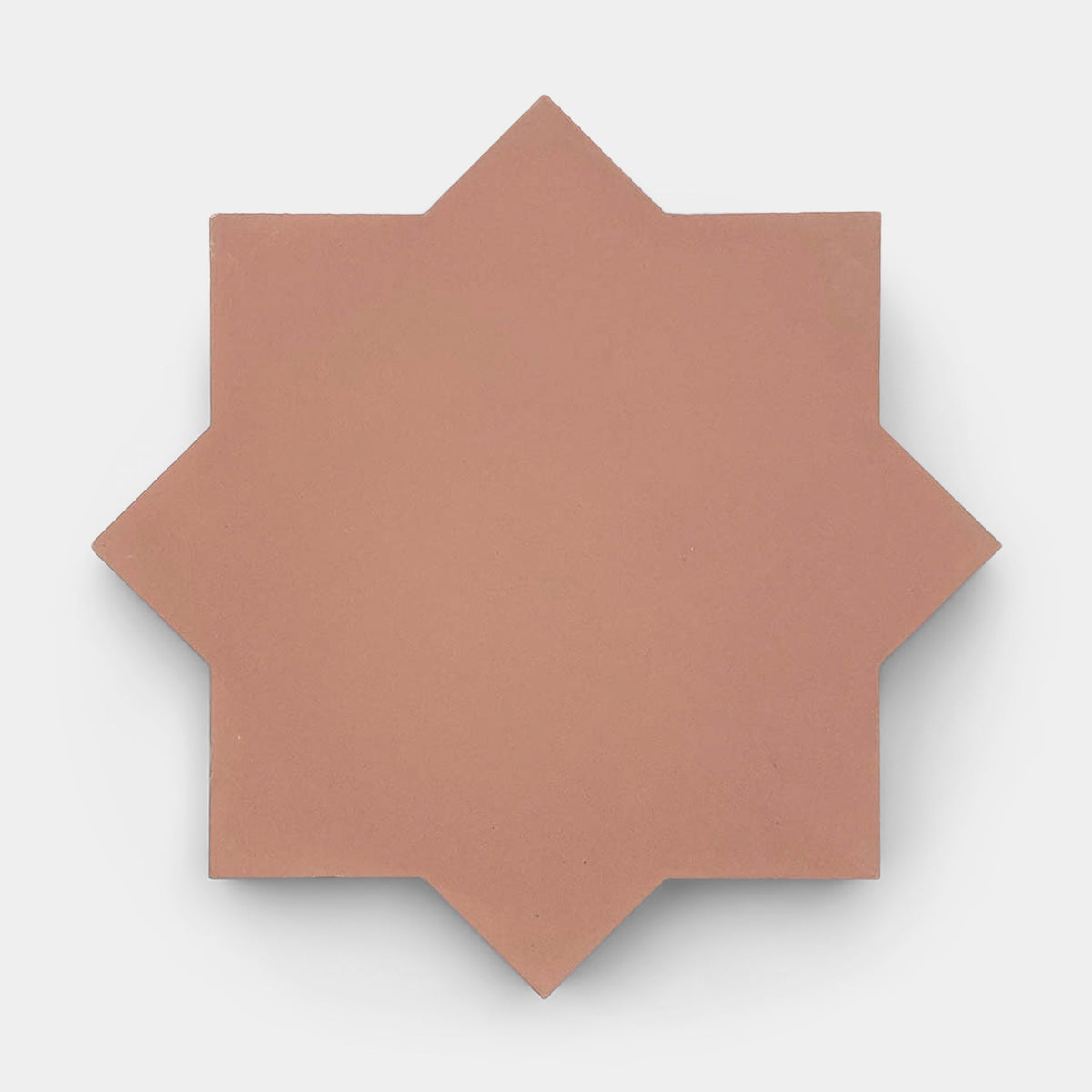 The Zia Tile Stars & Cross + Oscura sample, a flat, terracotta-toned tile with an eight-pointed star shape, is displayed against a plain white background.