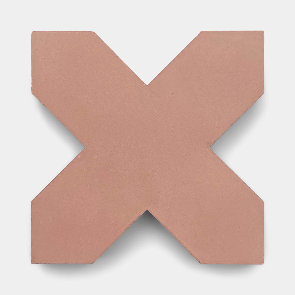 A pink, X-shaped Stars & Cross + Oscura sample tile by Zia Tile with sharp edges is centered on a light gray background, casting a subtle shadow below.