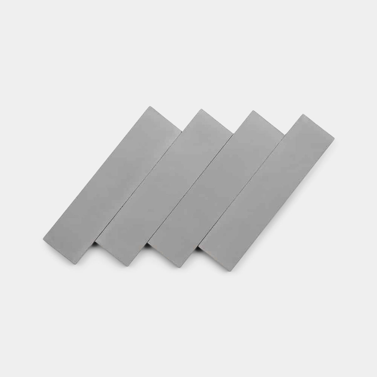 Four gray Steel 4x4 samples by Zia Tile, shaped like handmade tiles, are arranged diagonally and slightly overlapping on a plain white background.