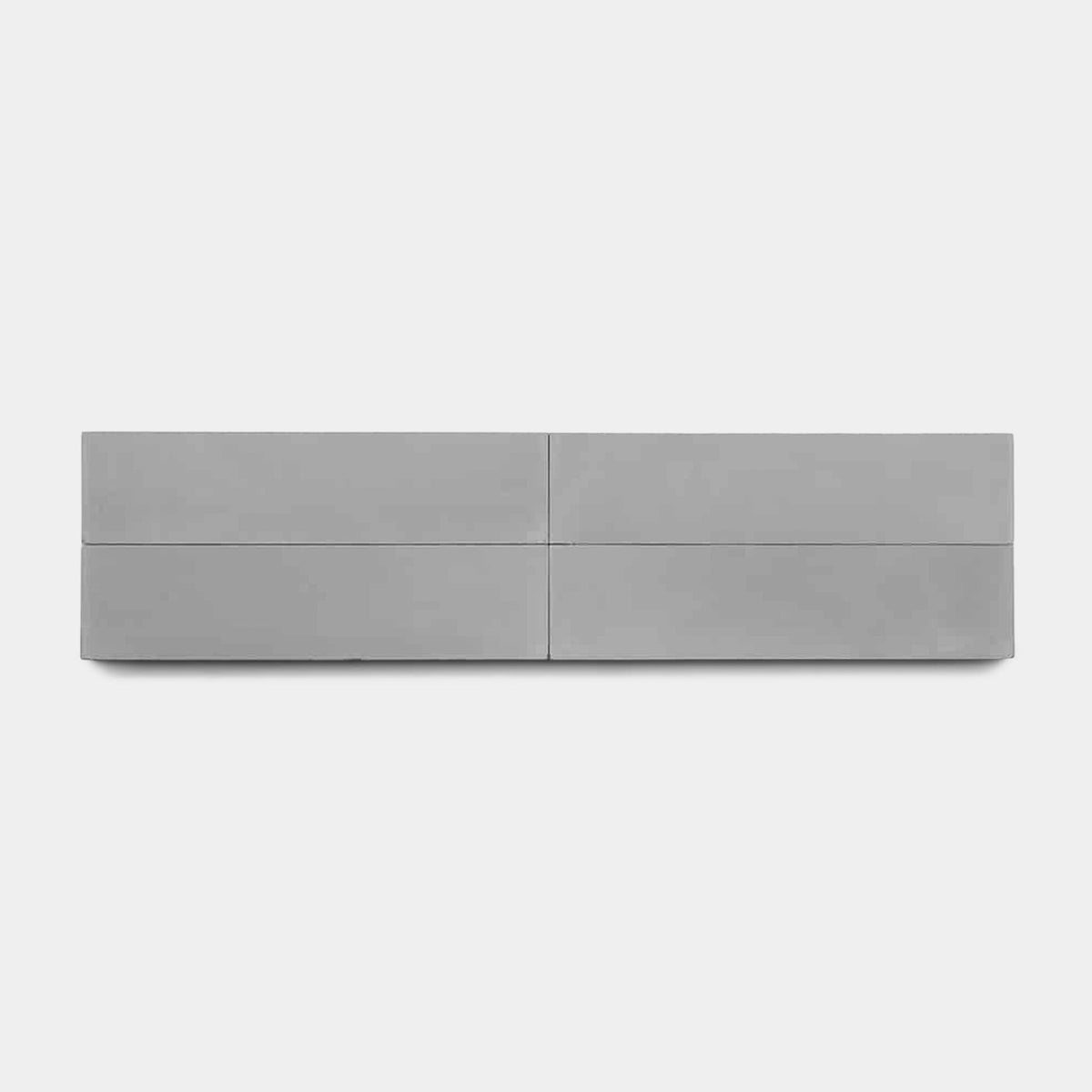 A minimalist gray wall-mounted cabinet with four horizontal drawers stands out above Zia Tile's Steel 4x4 sample, creating a modern look against a plain white background.