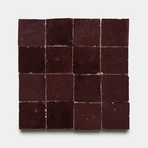 A 4x4 grid of sixteen Sumac 2x2 tiles by Zia Tile, featuring a dark brown textured finish, is displayed neatly arranged against a plain white background.