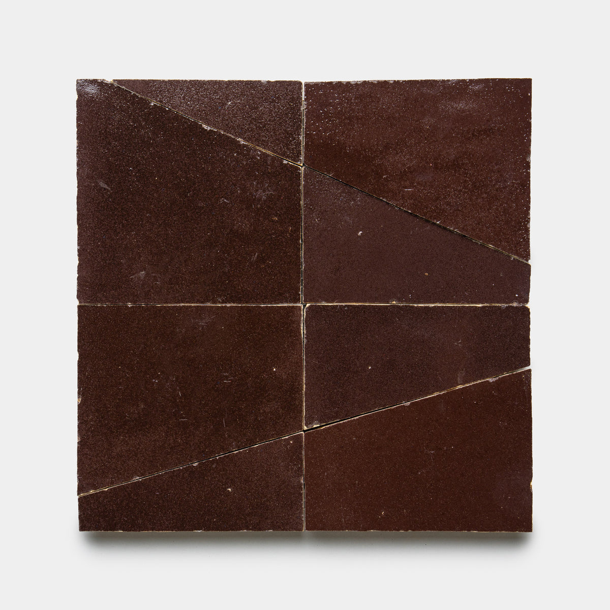Four Atlas 1 tiles by Zia Tile, dark brown in color, are arranged in a grid with each tile sliced diagonally to form triangles, creating a geometric pattern on a white background.