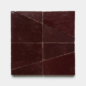 Atlas 1 by Zia Tile features four square burgundy tiles in a grid, each with a diagonal cut that forms two triangles. The tiles have a slightly textured surface and create an abstract geometric pattern when arranged together.