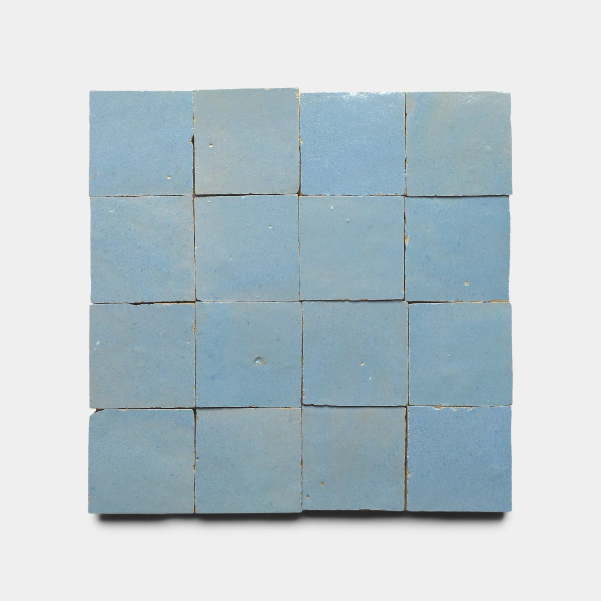 A 4x4 grid of Superior Blue 2x2 sample tiles by Zia Tile, arranged on a white background. These handmade tiles feature a light blue hue and slightly rough, artisanal texture reminiscent of classic cement tile.