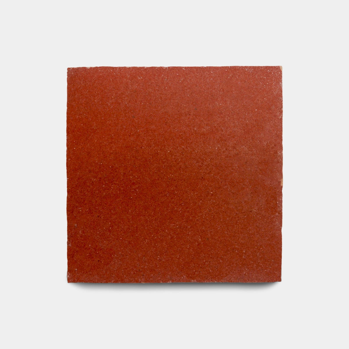 A Terra Rosa 2x2 cement tile sample from Zia Tile, in red with a slightly textured surface, displayed against a plain light gray background.