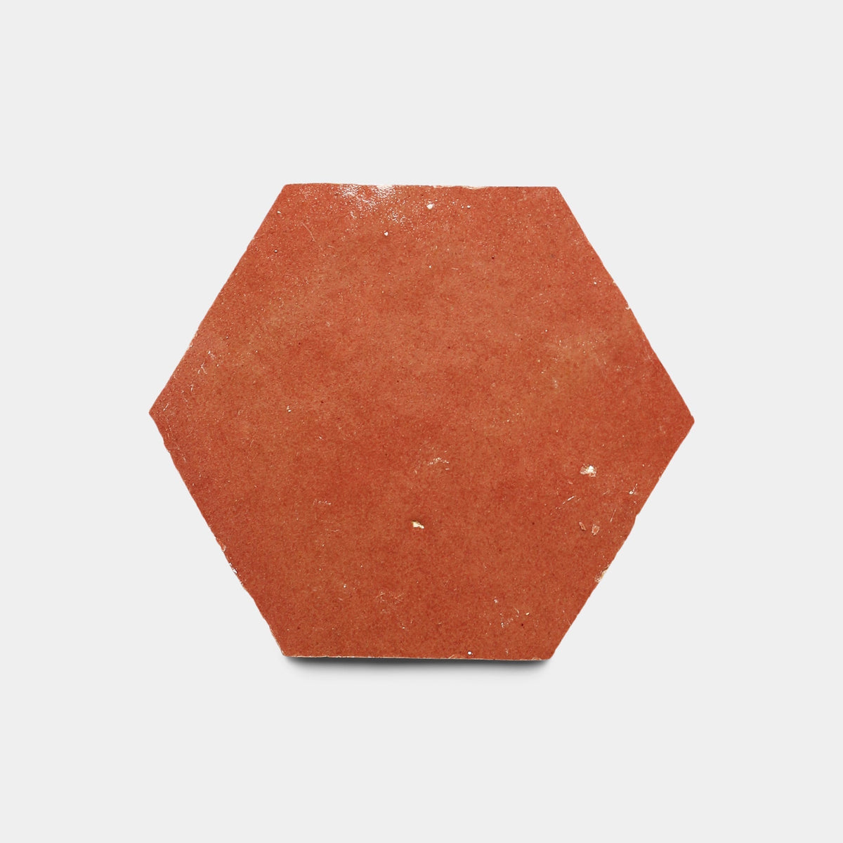 The Terra Rosa 2x2 sample by Zia Tile is a handmade hexagonal terracotta tile with a matte, slightly textured surface and minor imperfections, shown against a plain white background.