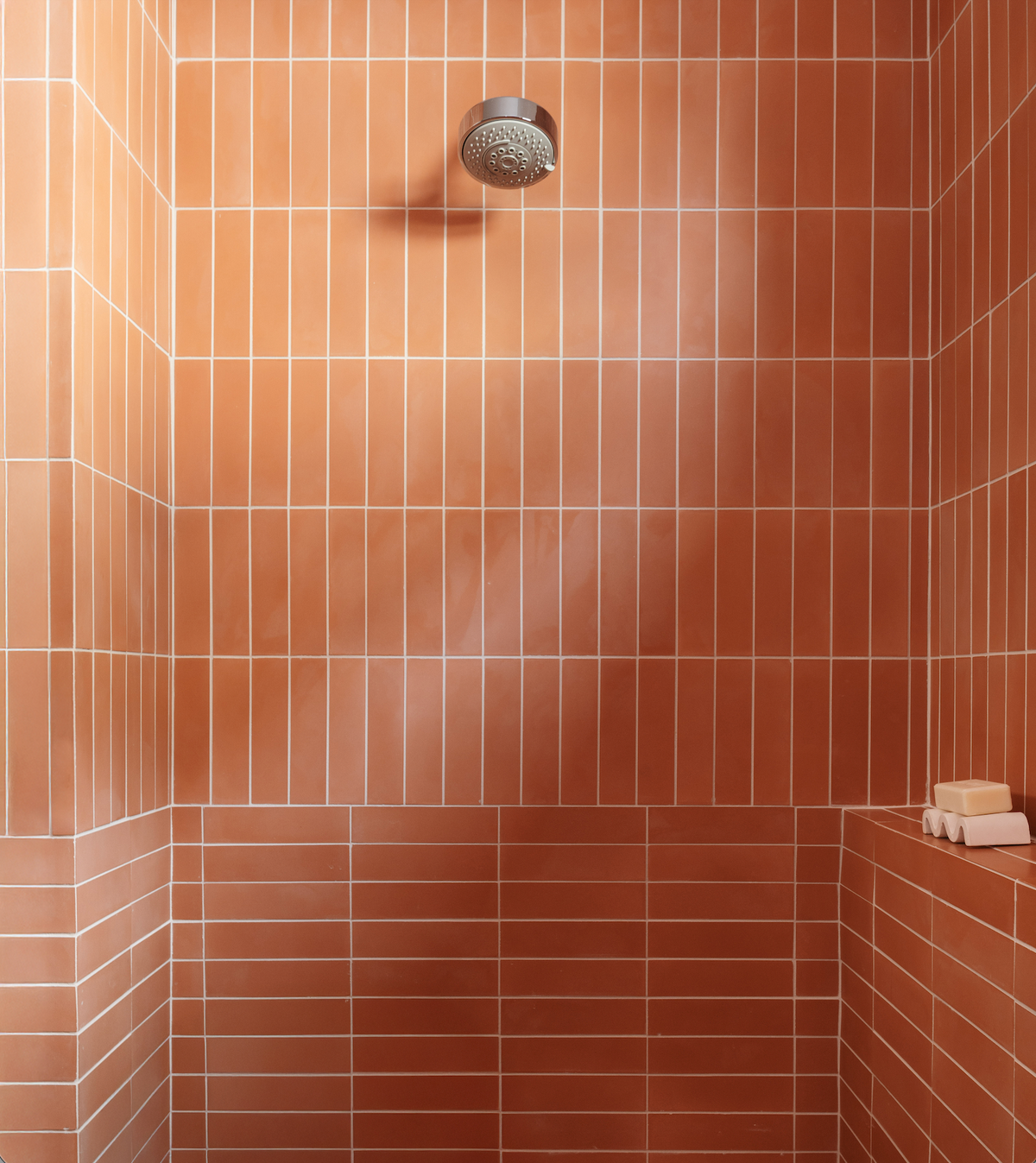 Enjoy a shower with a sleek shower head and classic Terra Cotta 2x8 tiles by vendor-unknown adding timeless style.