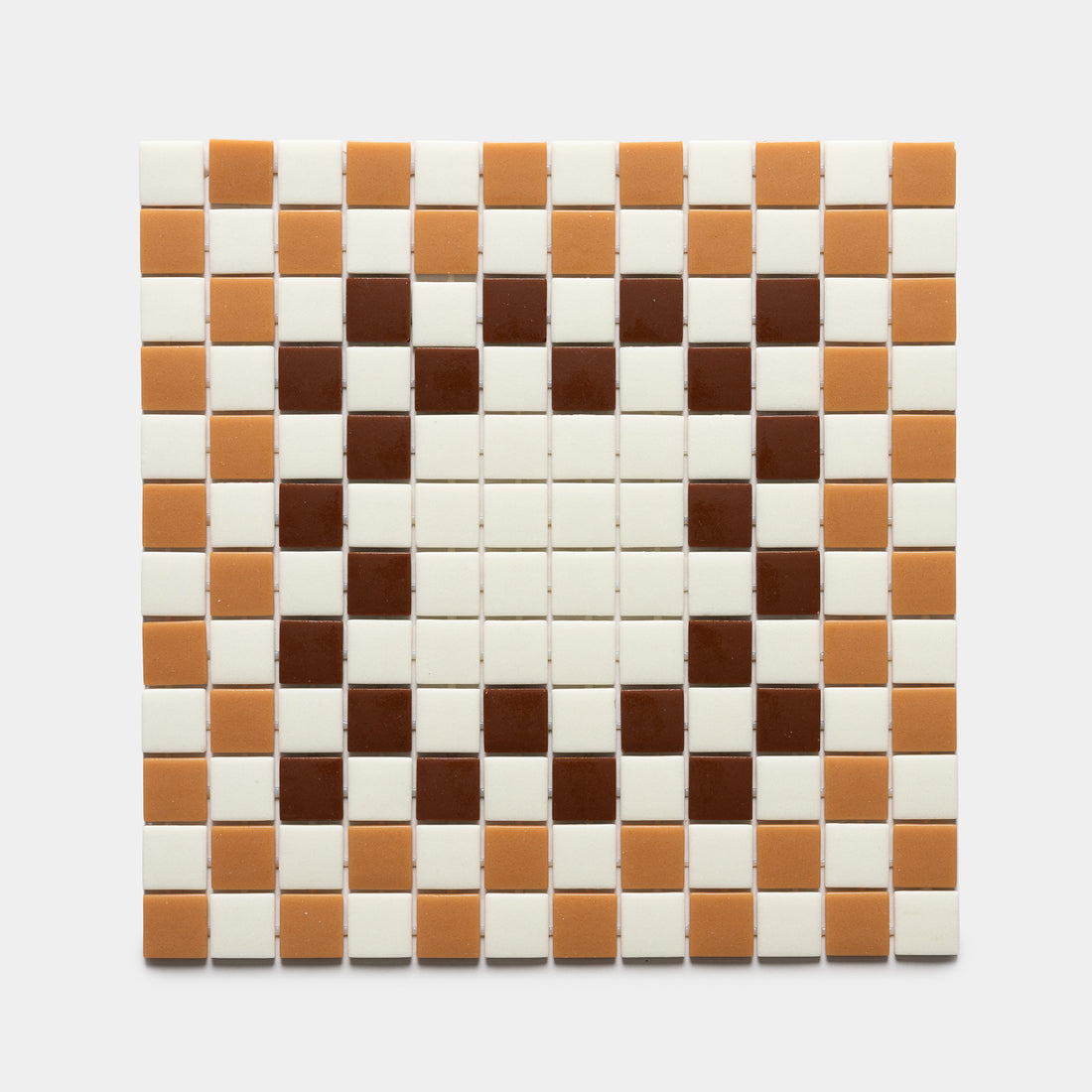 A heart shape made from Zia Tile's Tesserae Milk + Camel + Umber sample features dark brown (Umber) tiles for the heart, surrounded by tan (Camel) and cream (Milk) tiles on a white background.