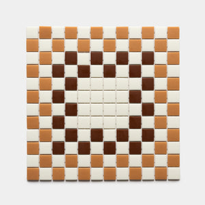 A heart shape made from Zia Tile's Tesserae Milk + Camel + Umber sample features dark brown (Umber) tiles for the heart, surrounded by tan (Camel) and cream (Milk) tiles on a white background.