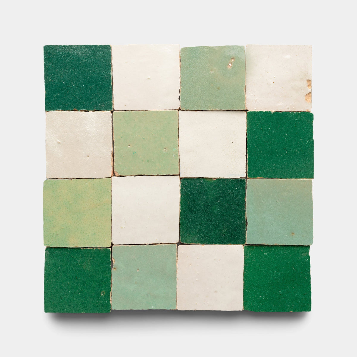 A sample of Zia Tile’s Tidepool + Casablanca + Jade Checkerboard features 16 ceramic tiles in green, white, and pale mint shades arranged in a checkerboard pattern on a light gray background.