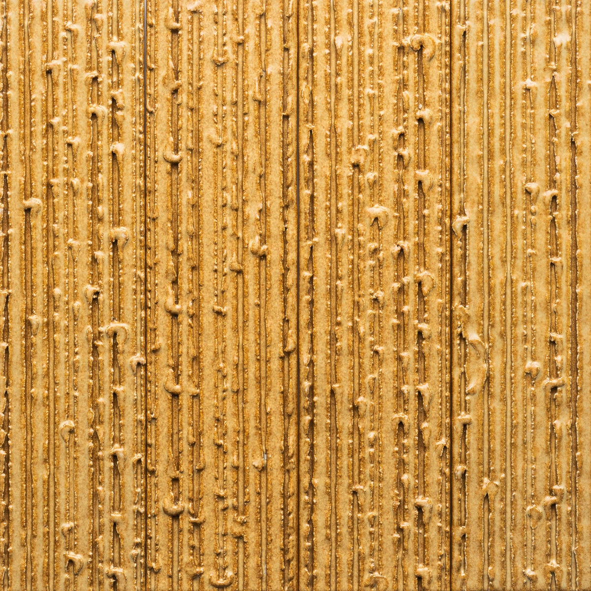 Close-up of Zia Tile's Toast + Furrowed Sample, showing a textured golden brown surface with vertical, uneven lines and small bumps reminiscent of wood grain or rugged material.