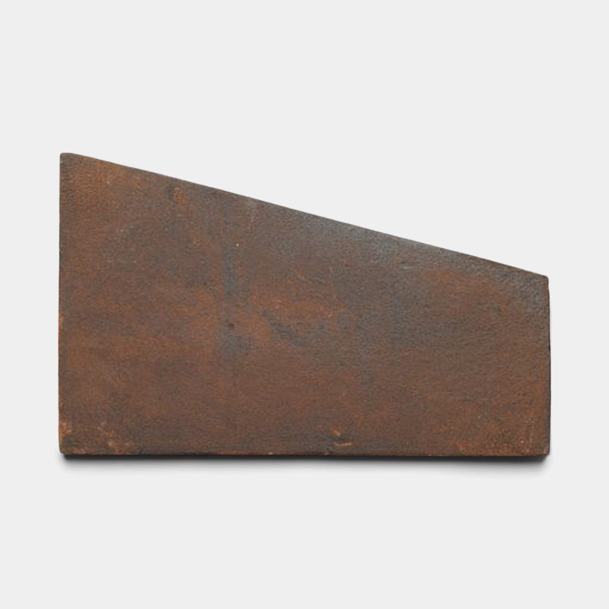 A Toltec + Madera sample by Zia Tile, featuring a wedge-shaped, slightly textured metal plate with a slanted top edge, reminiscent of a handmade tile, displayed against a plain white background.