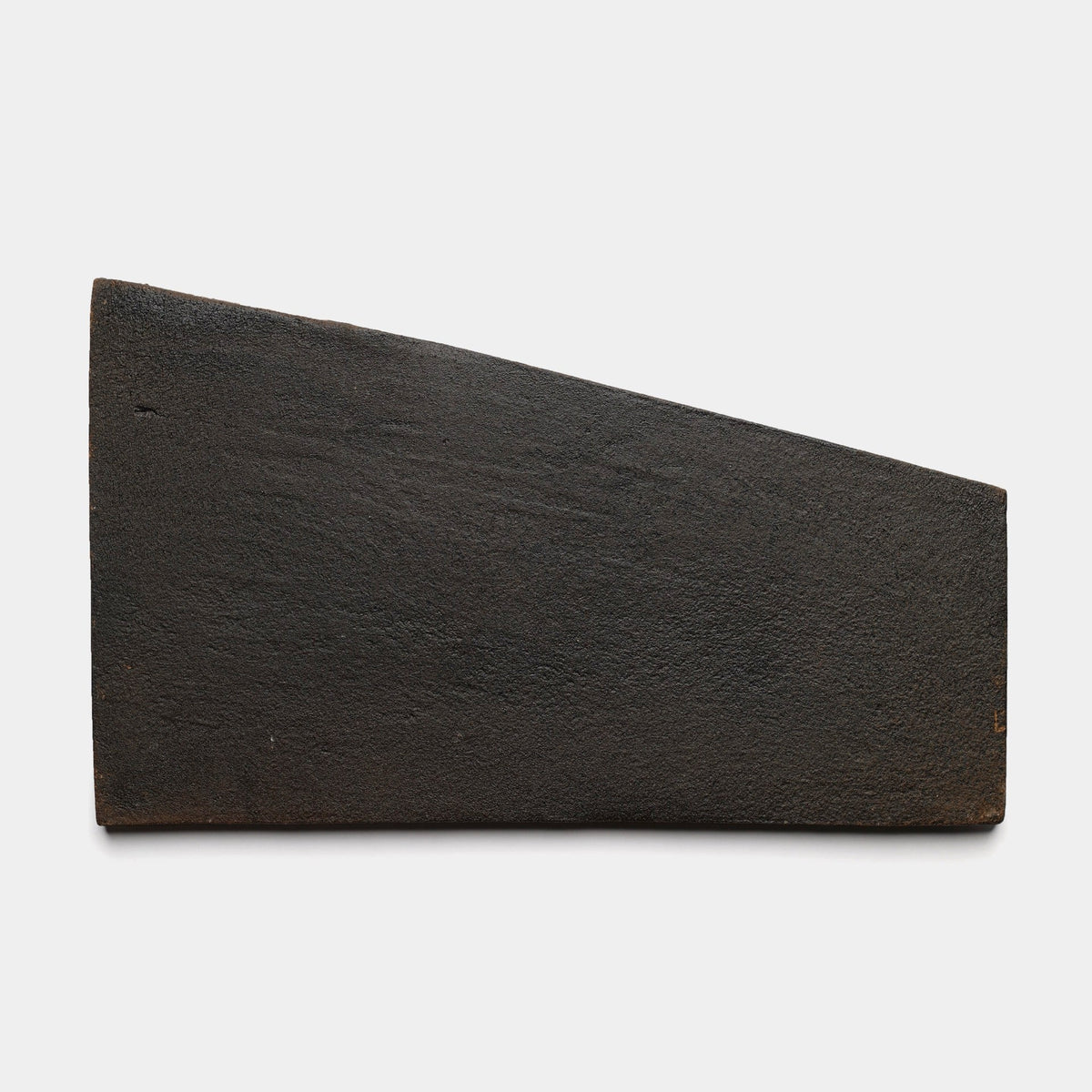 A rectangular, dark brown Toltec + Oscura sample tile by Zia Tile with a slightly uneven, wedge-shaped edge, displayed against a plain white background.