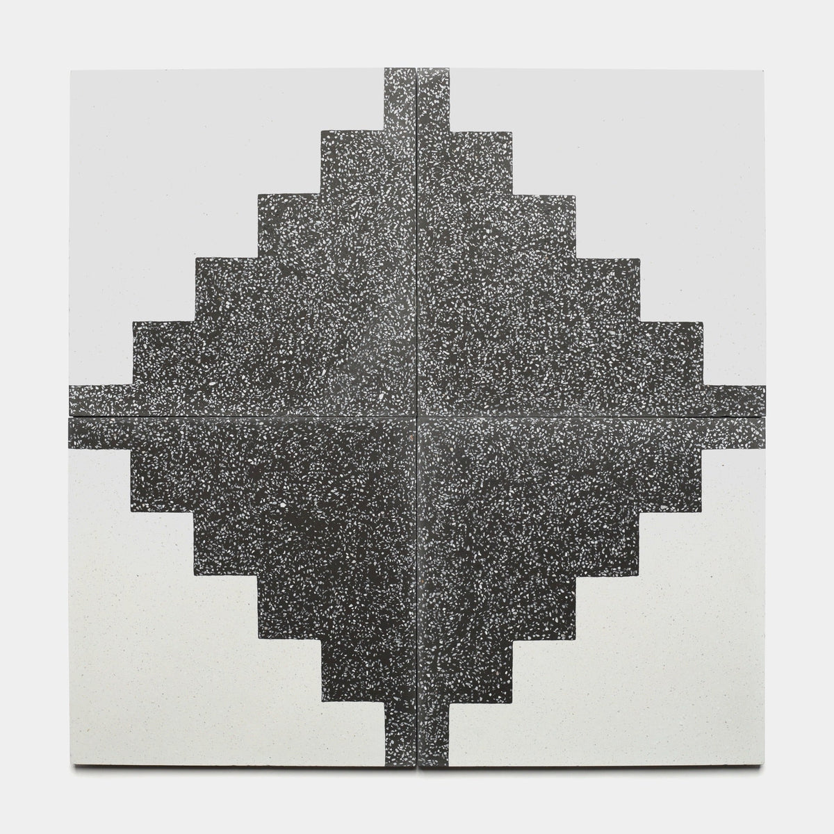 A geometric artwork featuring four Zia Tile Trellick Ash 12x12 tiles arranged in a symmetrical, pixelated black and white diamond pattern with speckled textures on a plain white background.