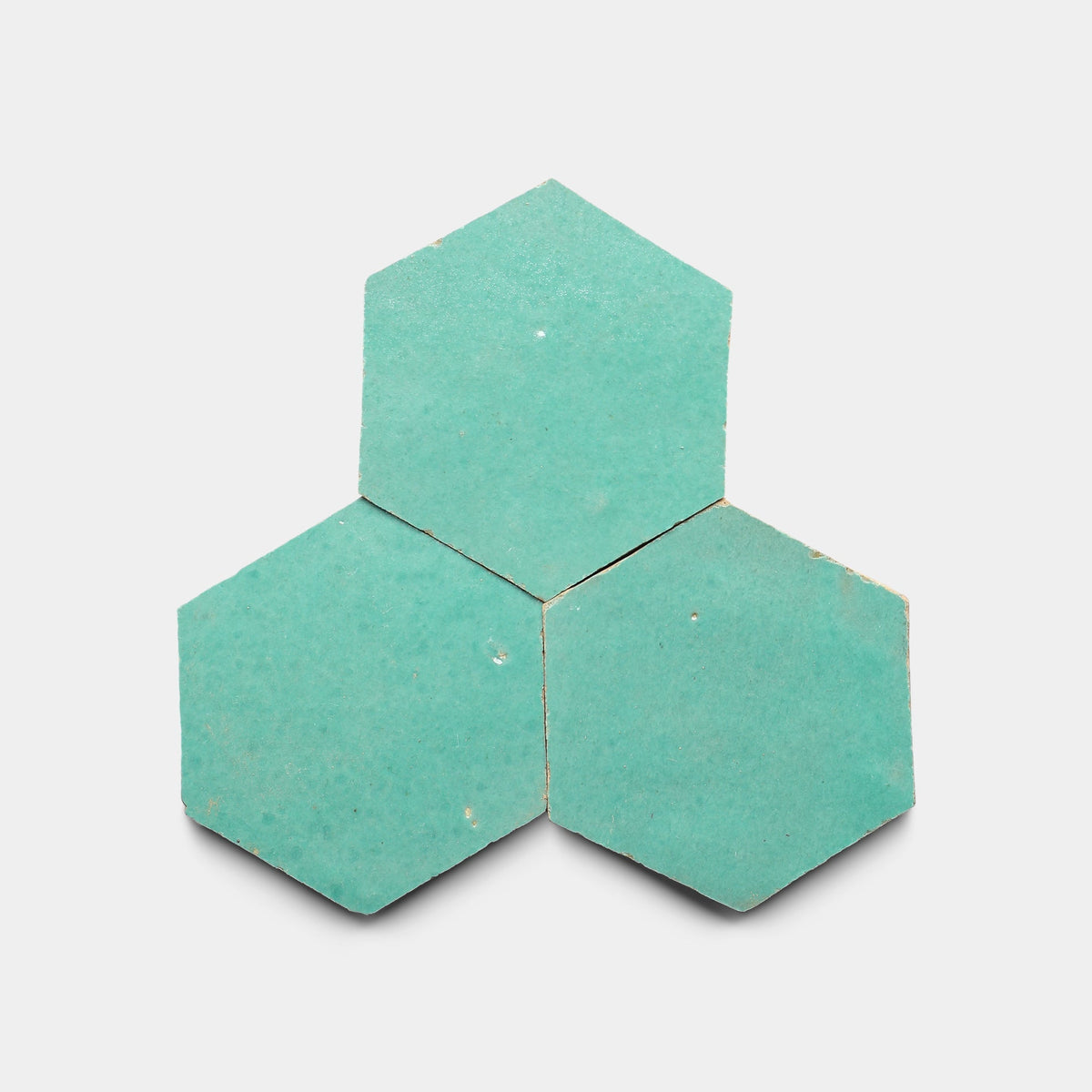 Three turquoise Tulum 2x2 cement tile samples from Zia Tile are arranged with one on top and two below in a triangle shape on a white background, reflecting Zia Tile's modern design aesthetic.