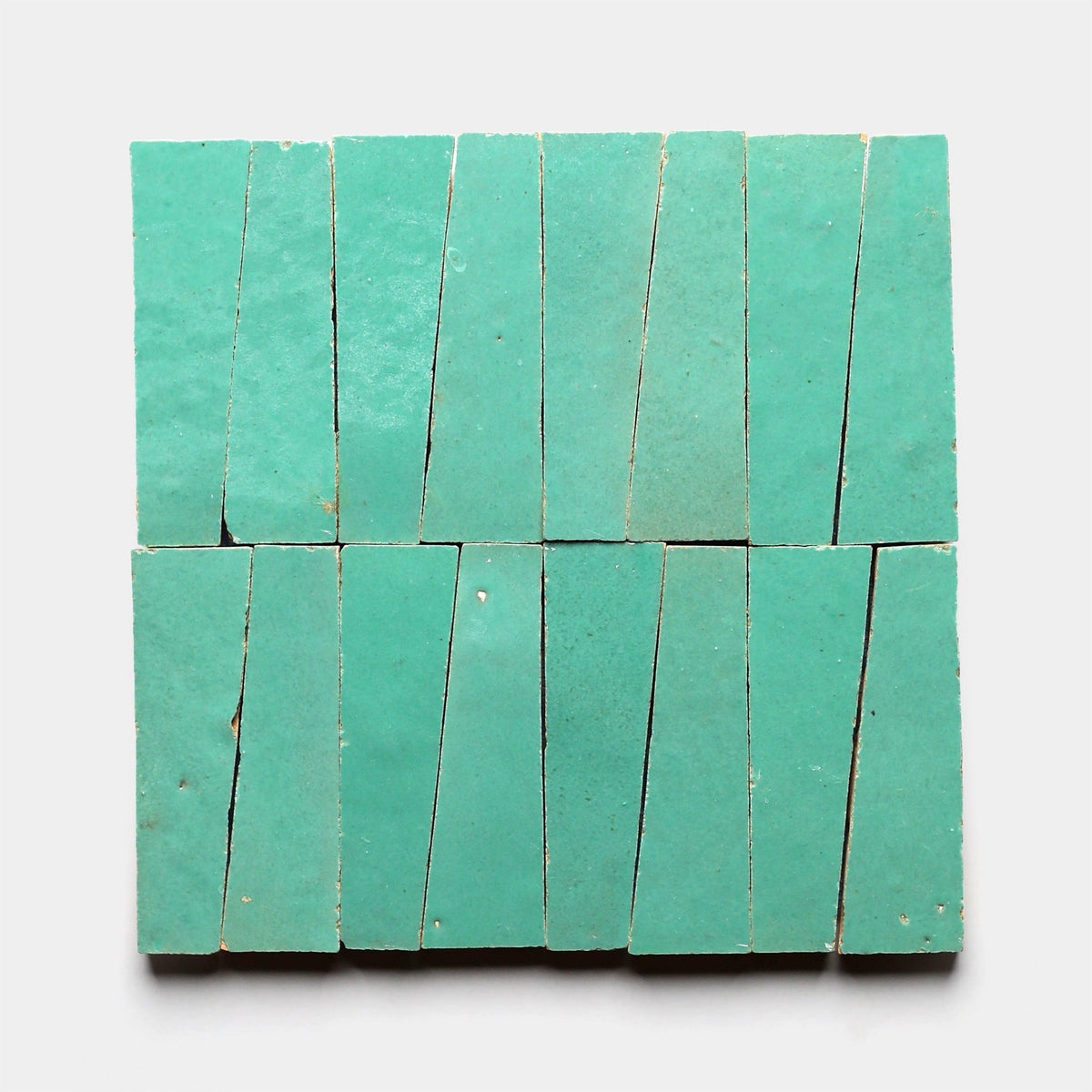 Sixteen Tulum Trapezoid, Sample tiles from Zia Tile, each an irregular quadrilateral, form a geometric square pattern on a white background.