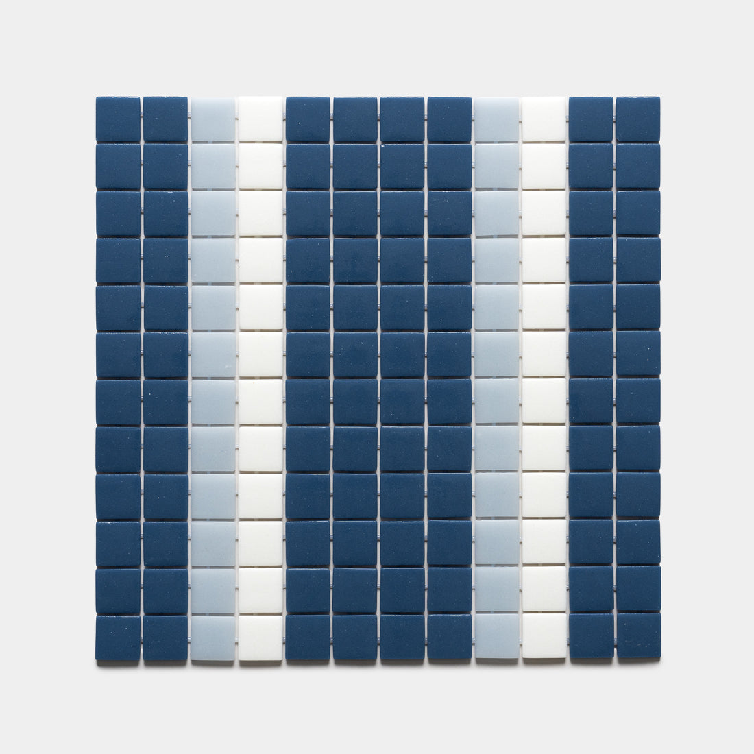 A grid of small square tiles in Union Damascus, Tranquil Blue, and Paperwhite by Zia Tile forms vertical stripes of dark blue, light blue, and white on a plain light background.