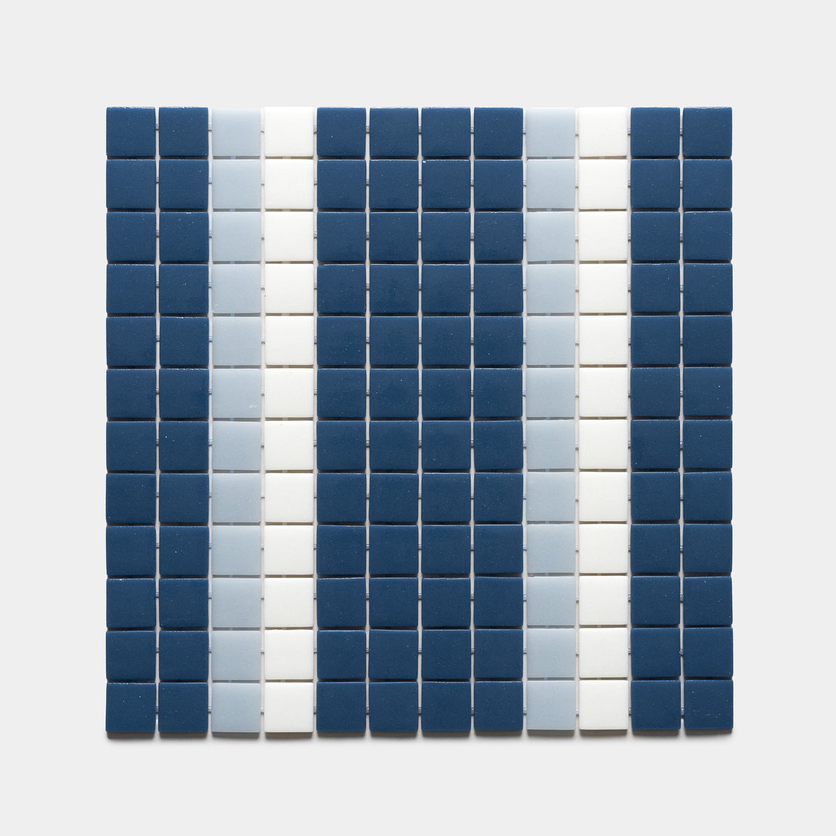 A grid of small square tiles in Union Damascus, Tranquil Blue, and Paperwhite by Zia Tile forms vertical stripes of dark blue, light blue, and white on a plain light background.