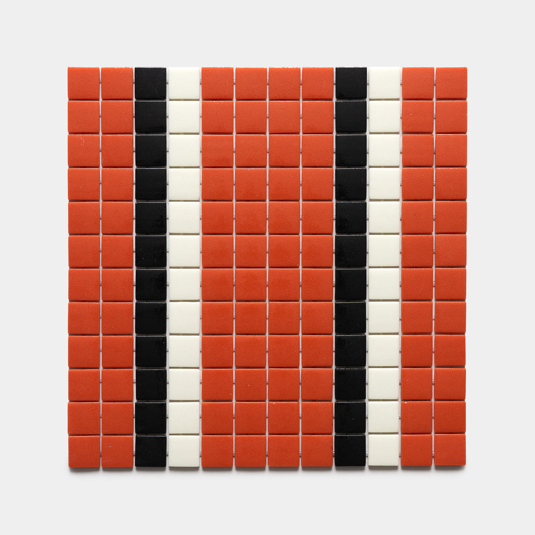 A rectangular grid of mostly red tiles with two vertical black stripes and two vertical white stripes on light gray, featuring Union Roma + Jet Black + Milk, Sample by Zia Tile.