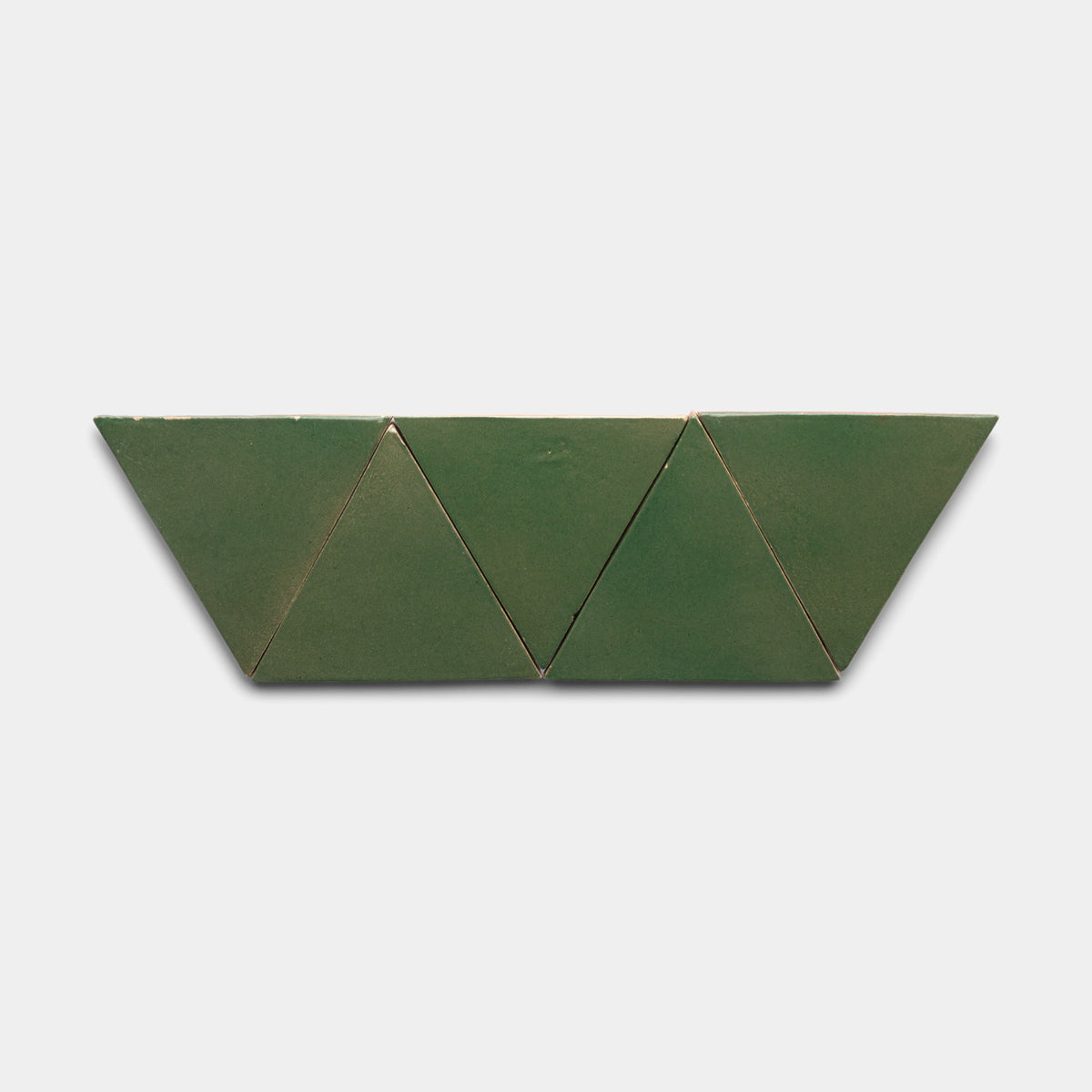 Three Valverde Triangle tiles by Zia Tile, in green cardboard, are arranged side by side in a zigzag pattern on a plain white background.
