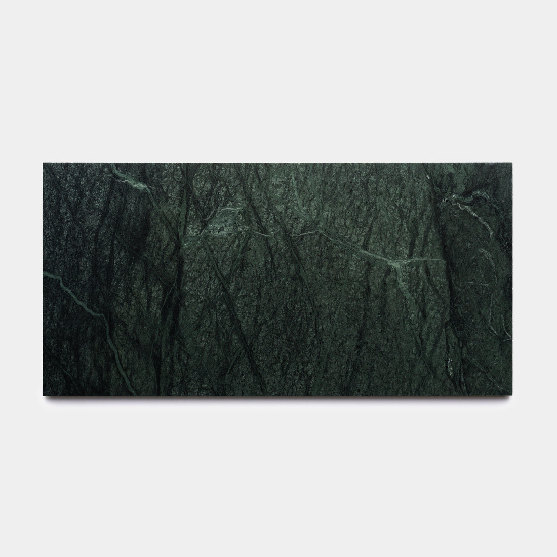 The Verde Alpi 12x24 by Zia Tile is a rectangular slab of dark green marble with natural veins running diagonally, reminiscent of a handmade tile. It is shown against a plain white background.