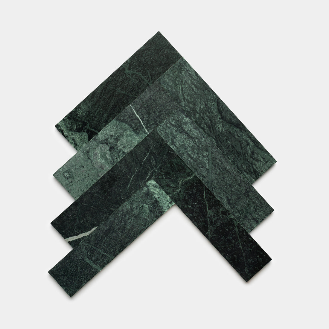 Four rectangular Verde Alpi 3x12 tiles by Zia Tile, in deep green marble, are arranged in a layered chevron pattern on a plain white background.