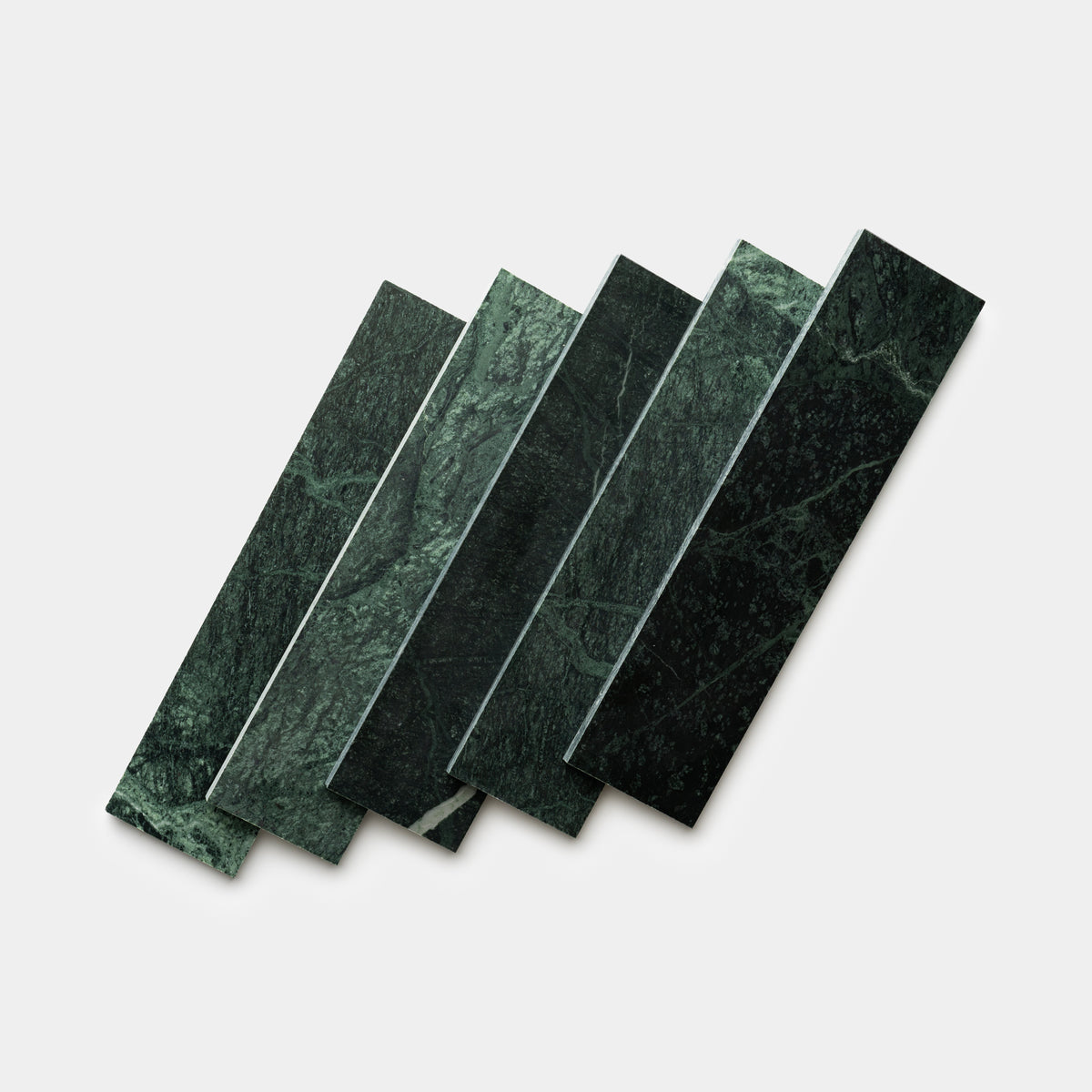 Five Verde Alpi 3x12 rectangular tiles by Zia Tile, featuring green marble with white veining, are arranged in a staggered, overlapping pattern on a plain white background.