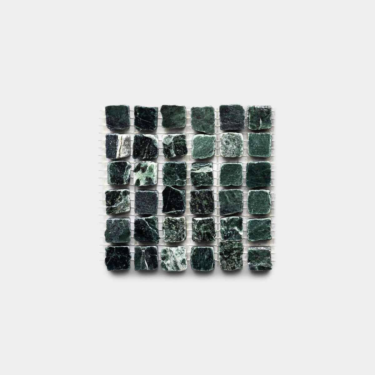 A square grid of Zia Tile’s Verde Alpi 5/8 sample—small, dark green stone tiles with textured surfaces and unique marbling—creates a varied, natural pattern against a white background.
