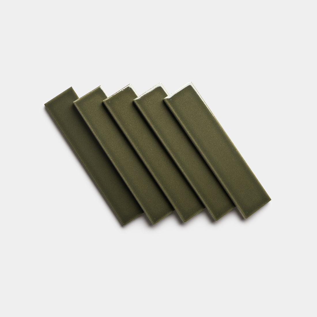 Six Vetiver 2x8 rectangular ceramic tiles by Zia Tile, in olive green, are arranged diagonally in a fanned-out pattern on a plain white background.