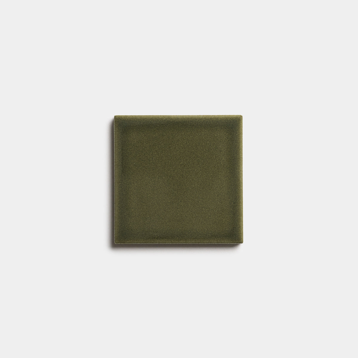 A single Vetiver 4x4 ceramic tile by Zia Tile, featuring a matte olive green finish, is centered on a plain white background.